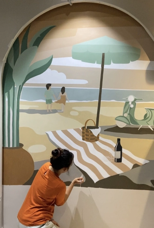 Mural artist in India painting a beach-themed wall mural inspired by creativity, storytelling, and artistic expression.